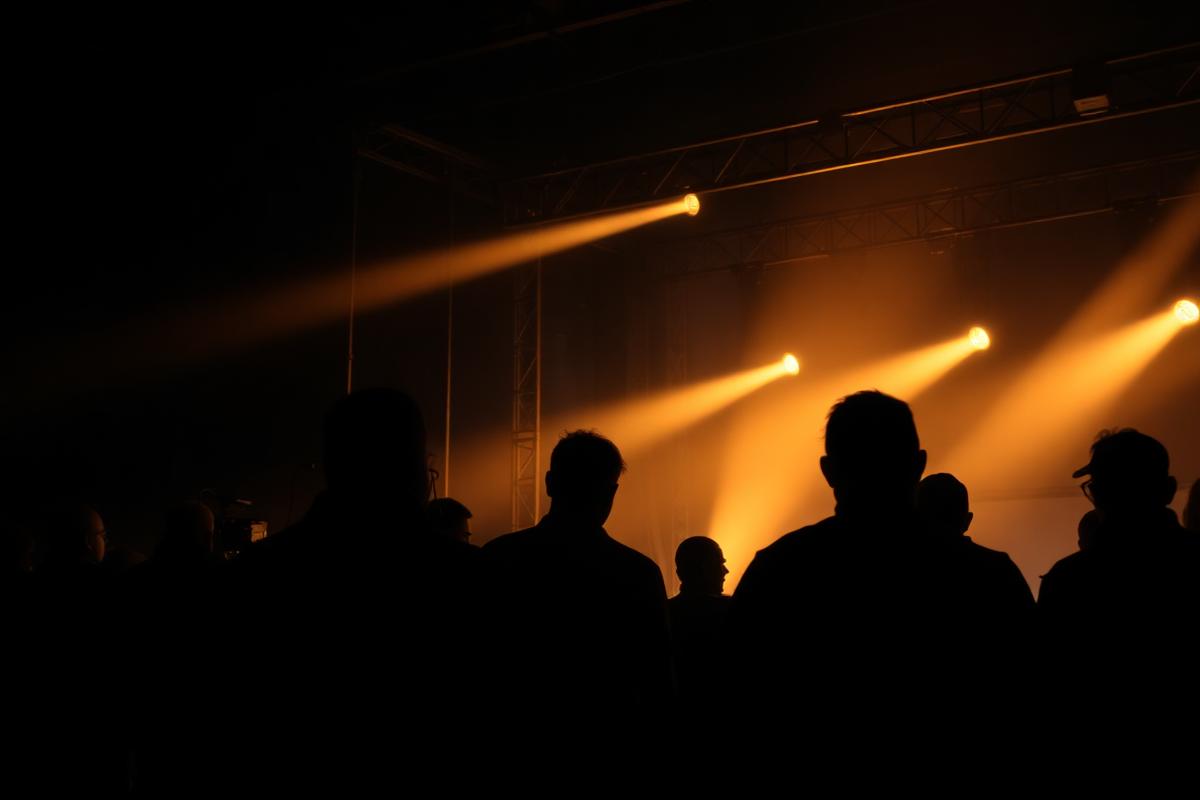 Stage lighting rig and crew silhouettes at an MPSC live event